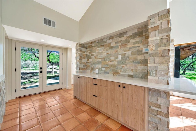 interior space featuring french doors, high vaulted ceiling, visible vents, light countertops, and light brown cabinets