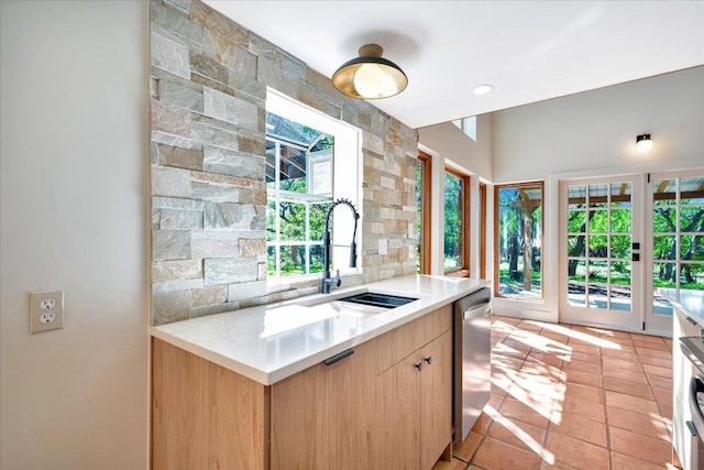 kitchen featuring light countertops, light brown cabinets, a sink, and dishwasher