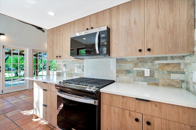 kitchen featuring light tile patterned floors, light brown cabinetry, stainless steel appliances, modern cabinets, and backsplash