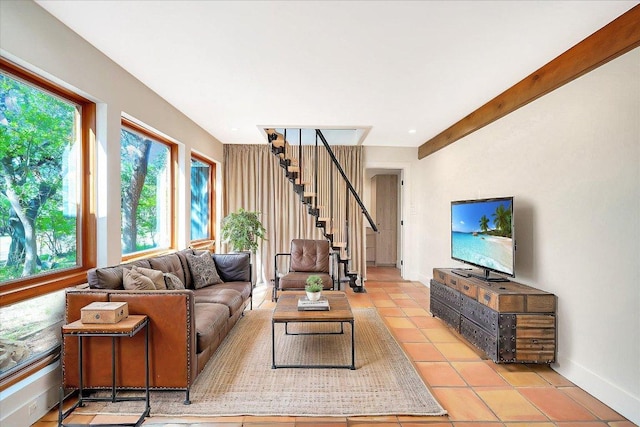 living room featuring light tile patterned floors, baseboards, and stairs