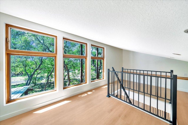 bonus room featuring a textured ceiling, baseboards, and wood finished floors