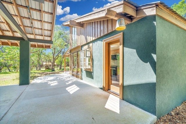 view of property exterior featuring board and batten siding, a patio area, and stucco siding