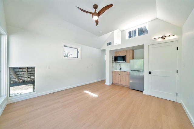 unfurnished living room featuring visible vents, light wood-style flooring, lofted ceiling, and a sink