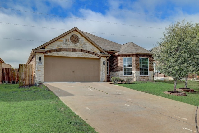 view of front of property featuring fence, stone siding, driveway, a garage, and a front lawn