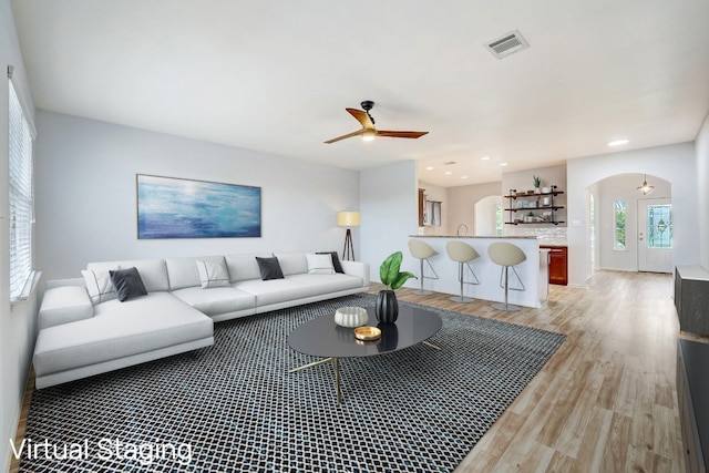 living room featuring visible vents, recessed lighting, ceiling fan, arched walkways, and light wood-style floors