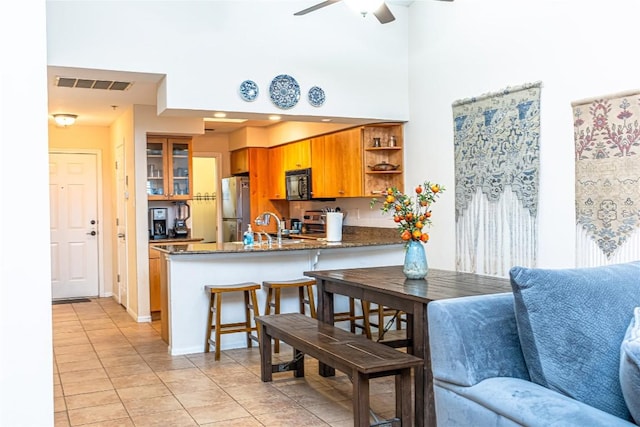 kitchen with freestanding refrigerator, light tile patterned floors, visible vents, black microwave, and open shelves