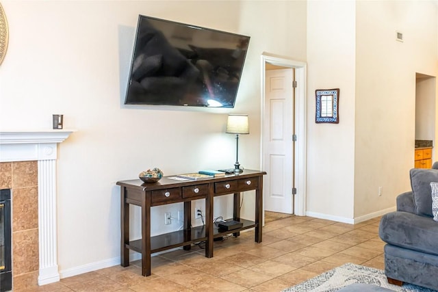 living room with a tile fireplace, light tile patterned floors, baseboards, and a towering ceiling