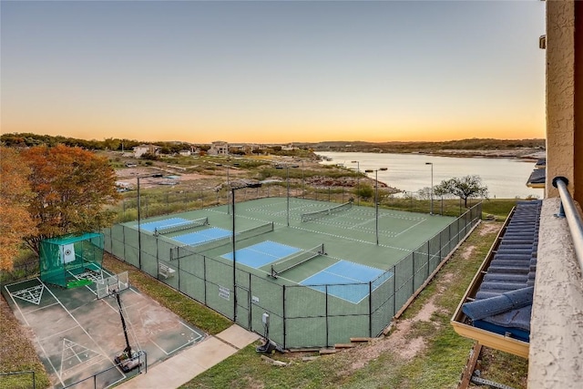 view of sport court featuring a water view and fence
