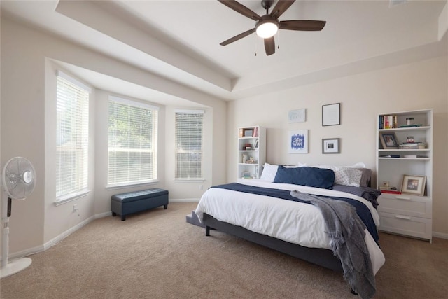 carpeted bedroom featuring baseboards, a raised ceiling, and a ceiling fan