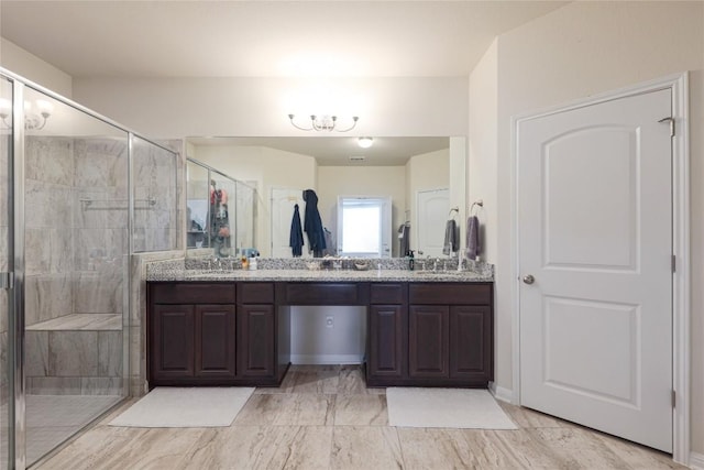 full bathroom with a sink, double vanity, a stall shower, and an inviting chandelier