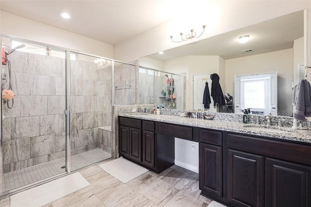 bathroom with a sink, double vanity, a shower stall, and visible vents