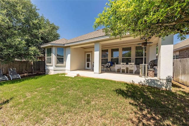 back of house featuring a lawn, stucco siding, and fence
