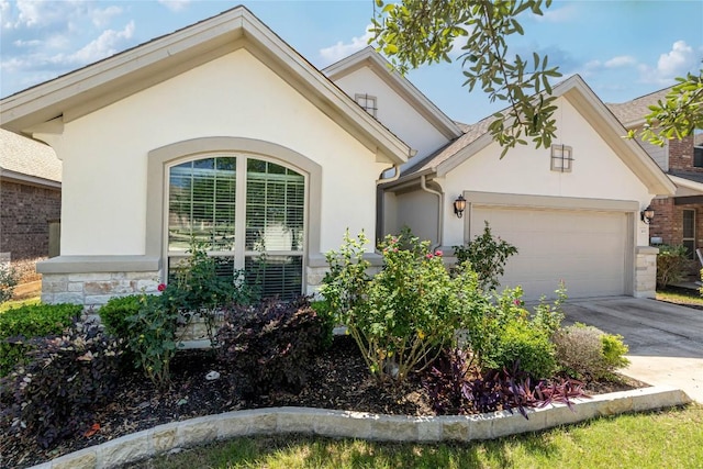 view of front of house featuring a garage, stucco siding, stone siding, and driveway