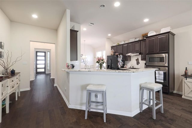 kitchen featuring a kitchen breakfast bar, a healthy amount of sunlight, tasteful backsplash, and appliances with stainless steel finishes