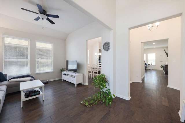 living area with lofted ceiling, dark wood-style flooring, baseboards, and ceiling fan with notable chandelier