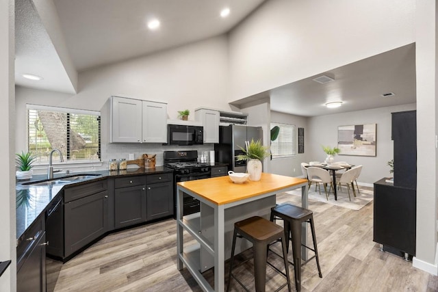 13105 Lubbock Ln, Austin, TX 78729 - kitchen with black appliances, high vaulted ceiling, light wood-style flooring, tasteful backsplash, and wooden counters
