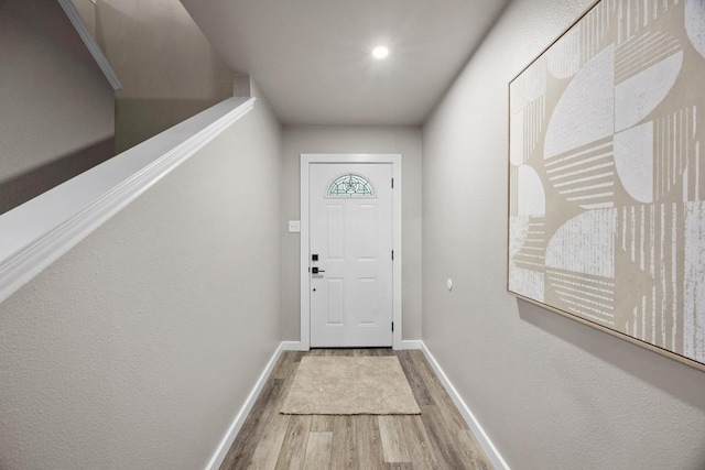 doorway to outside featuring baseboards and wood finished floors