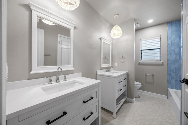 full bath featuring toilet, baseboards, two vanities, and a sink