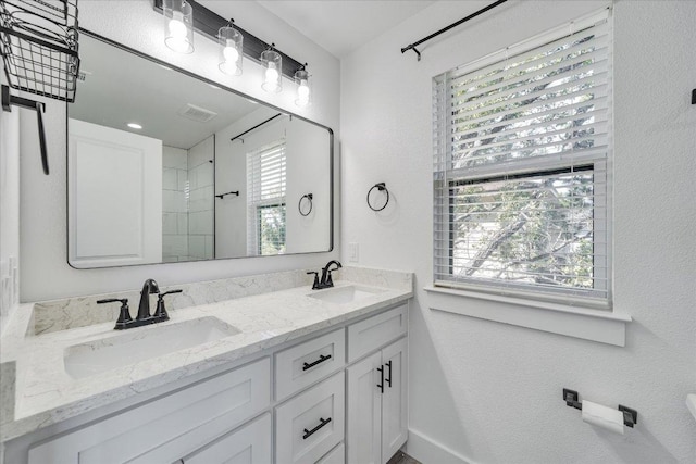 294 Shady Bluff Dr, Wimberley, TX 78676 - bathroom with double vanity, visible vents, tiled shower, and a sink