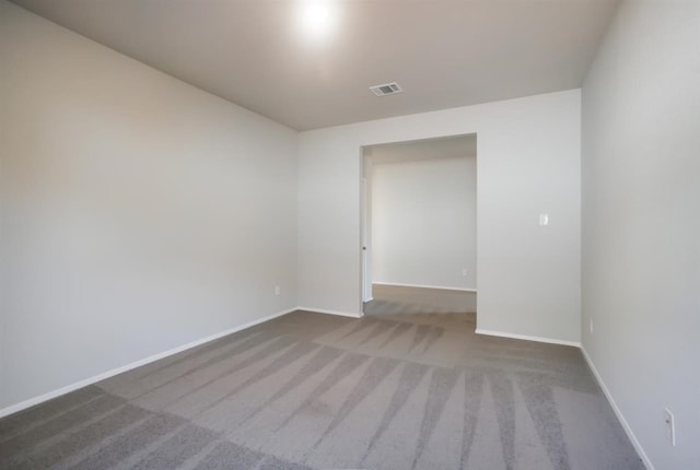 carpeted spare room featuring baseboards and visible vents