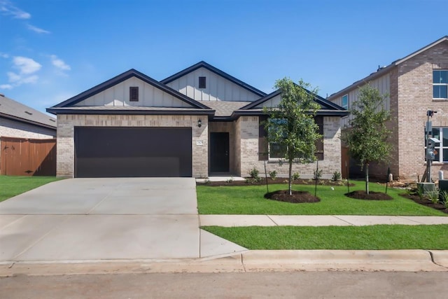 view of front of home with an attached garage, brick siding, driveway, a front yard, and board and batten siding