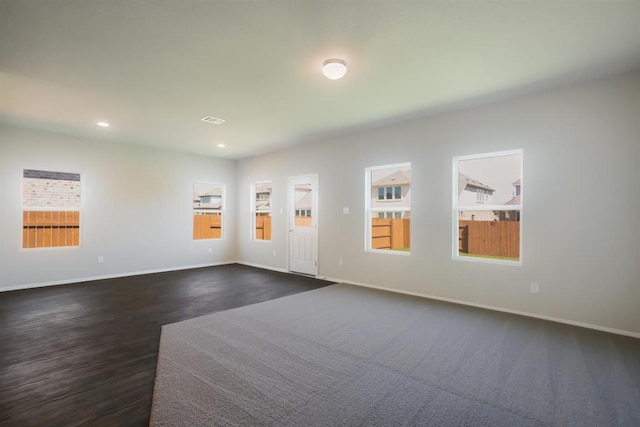 spare room featuring a wealth of natural light, baseboards, and dark wood finished floors