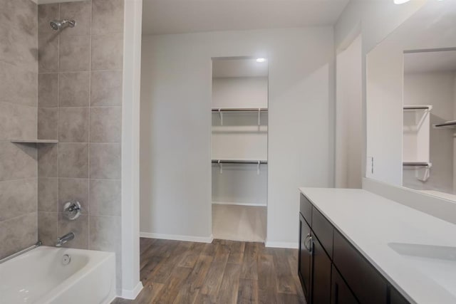 bathroom with vanity, shower / washtub combination, baseboards, and wood finished floors