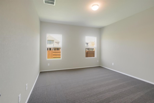 spare room with baseboards, visible vents, and dark carpet