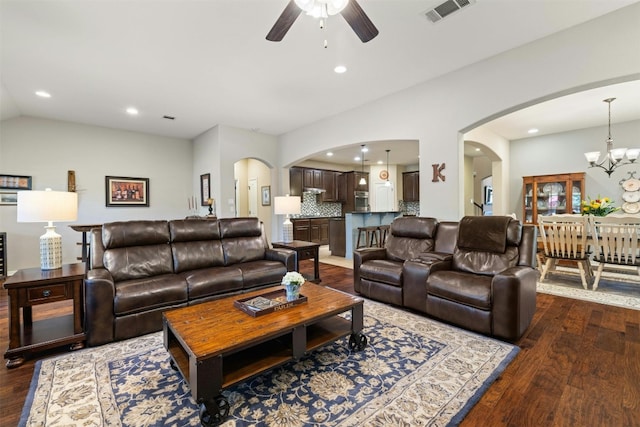 152 Florenz Ln, Georgetown, TX 78628 - living area featuring ceiling fan with notable chandelier, visible vents, vaulted ceiling, dark wood-style flooring, and arched walkways