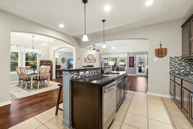 152 Florenz Ln, Georgetown, TX 78628 - kitchen featuring a sink, open floor plan, arched walkways, dishwasher, and decorative backsplash