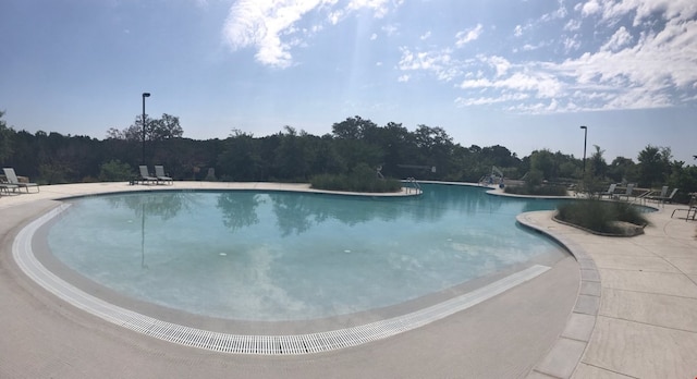 community pool with a patio and a wooded view