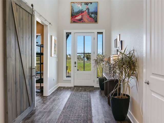 entryway featuring wood finished floors, a barn door, baseboards, and a high ceiling