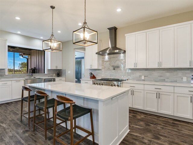 kitchen with wall chimney range hood, tasteful backsplash, dark wood-style flooring, light countertops, and range