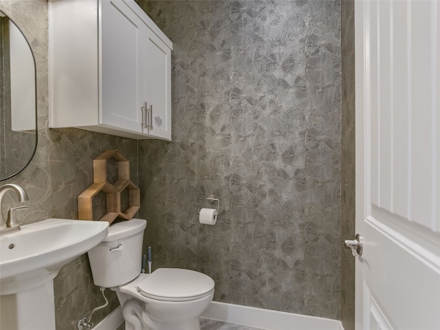 bathroom featuring a sink, curtained shower, toilet, and wallpapered walls