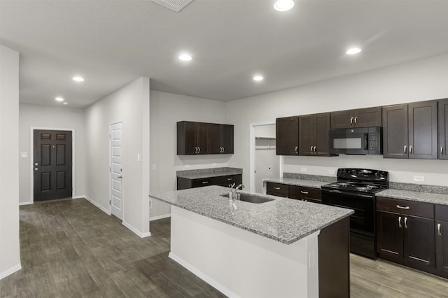 kitchen with recessed lighting, dark wood finished floors, a sink, black appliances, and an island with sink