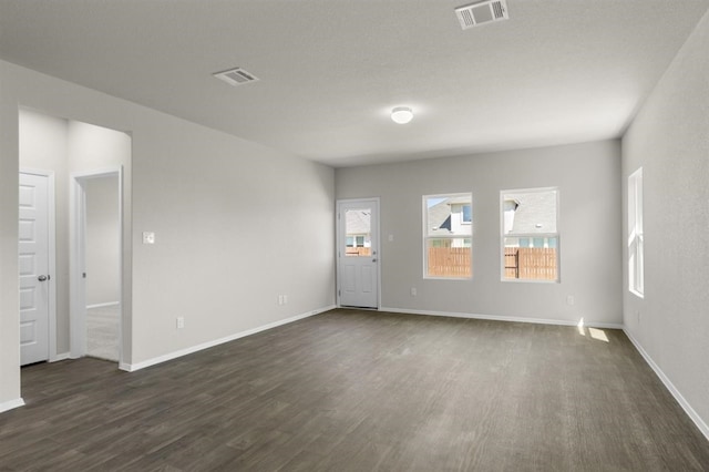 spare room featuring baseboards, dark wood-style flooring, and visible vents