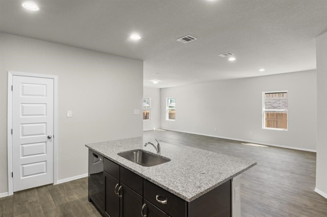 kitchen with a sink, a center island with sink, visible vents, baseboards, and dark wood-type flooring