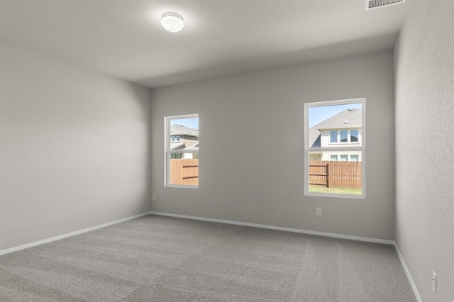 unfurnished room with visible vents, baseboards, a healthy amount of sunlight, and carpet floors