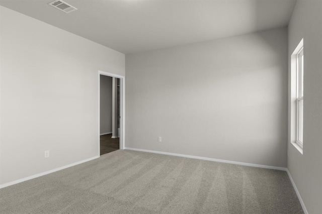 spare room with carpet, baseboards, and visible vents