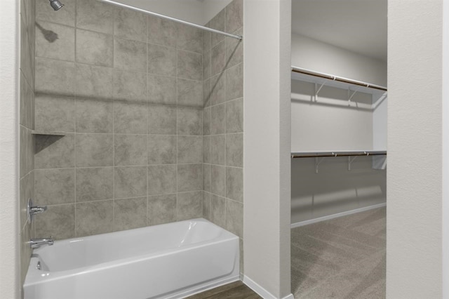 full bathroom with a walk in closet, baseboards, and bathtub / shower combination