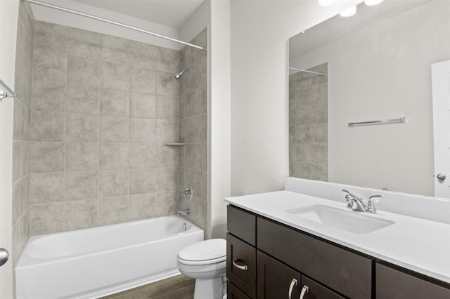 bathroom with toilet, wood finished floors, vanity, and washtub / shower combination