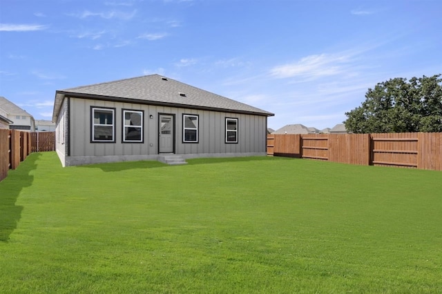 back of property featuring a yard, board and batten siding, a shingled roof, and a fenced backyard