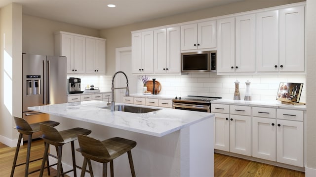 532 Bauer Loop, Liberty Hill, TX 78642 - kitchen with light wood-type flooring, a sink, white cabinetry, stainless steel appliances, and an island with sink