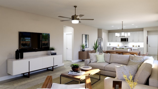 living room featuring light wood-type flooring, baseboards, ceiling fan, and recessed lighting