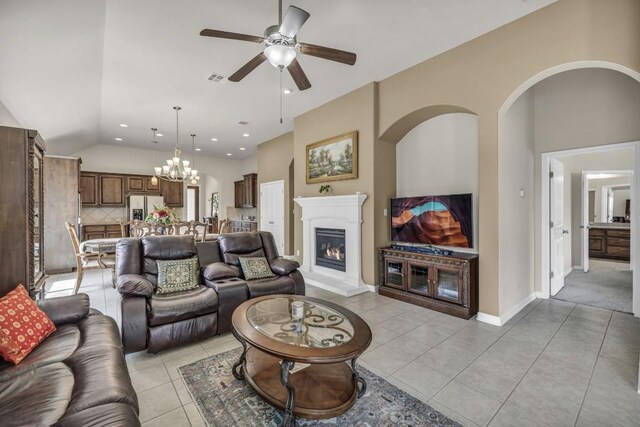 3821 Tordera Dr, Austin, TX 78738 - living area with visible vents, light tile patterned flooring, ceiling fan with notable chandelier, a lit fireplace, and vaulted ceiling