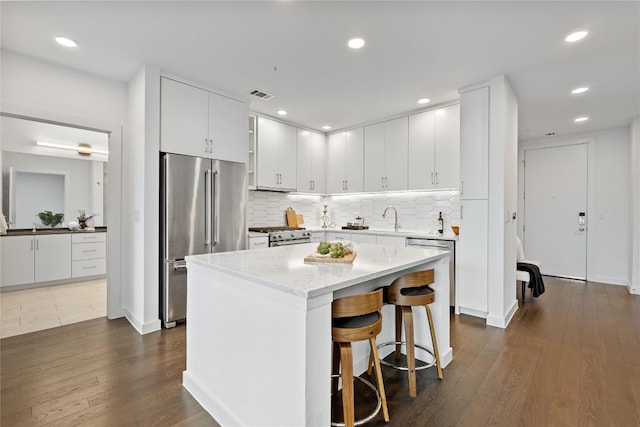 900 S 1st St S Unit 404, Austin, TX 78704 - kitchen with high end appliances, dark wood-style floors, white cabinetry, backsplash, and recessed lighting