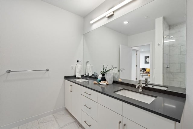 full bathroom featuring marble finish flooring, a stall shower, double vanity, and baseboards