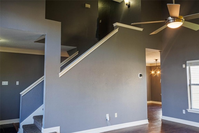 interior space with stairs, wood finished floors, crown molding, a ceiling fan, and baseboards