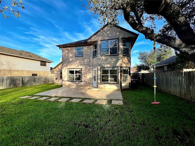 rear view of property with a yard, a patio area, and a fenced backyard