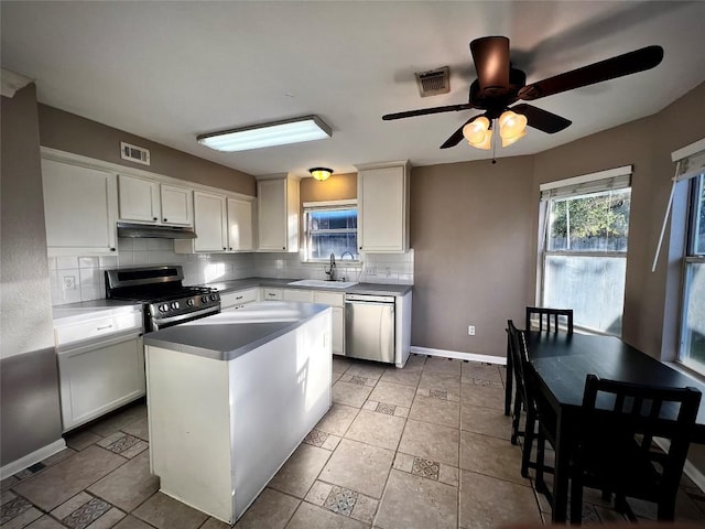 kitchen featuring under cabinet range hood, visible vents, a sink, stainless steel appliances, and tasteful backsplash